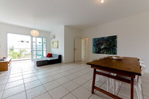 A spacious living area with a dining table, a sofa, and a large window. - Apt With Pool 250m From Jurere Beach Aya201 (Florianópolis)