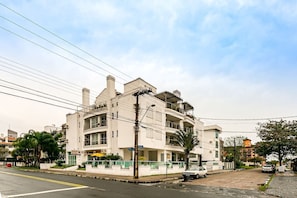 Un immeuble à plusieurs étages doté de balcons, une rue pavée et des voitures garées.