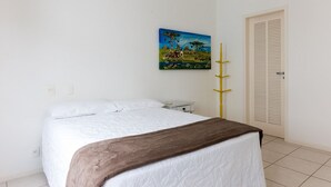 Un dormitorio con una cama, un cuadro en la pared, una mesita de noche y una puerta con paneles verticales.