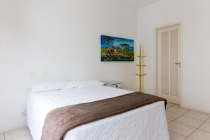Un dormitorio con una cama, un cuadro en la pared, una mesita de noche y una puerta con paneles verticales.