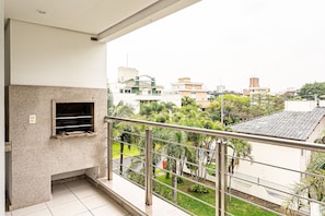 Un balcon doté d’une rambarde en métal, donnant sur un quartier résidentiel avec des maisons et de la verdure.