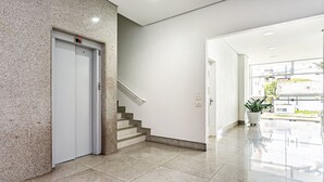 Un interior moderno con suelo de mármol, una escalera y una puerta con luz indicadora roja.