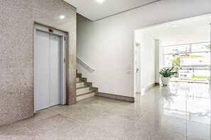 Un interior moderno con suelo de mármol, una escalera y una puerta con luz indicadora roja.