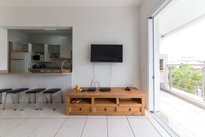 Cocina moderna con televisor de pantalla plana, taburetes de madera y un amplio ventanal con vistas al exterior.