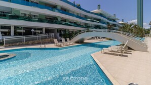 Et moderne hotel med swimmingpool, flere altaner og en bro der forbinder forskellige niveauer.
