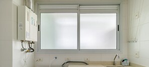 Ein Waschraum mit Waschmaschine, Spüle und Fenster.