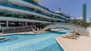 Um hotel moderno com piscina, várias varandas e uma ponte que liga diferentes andares.