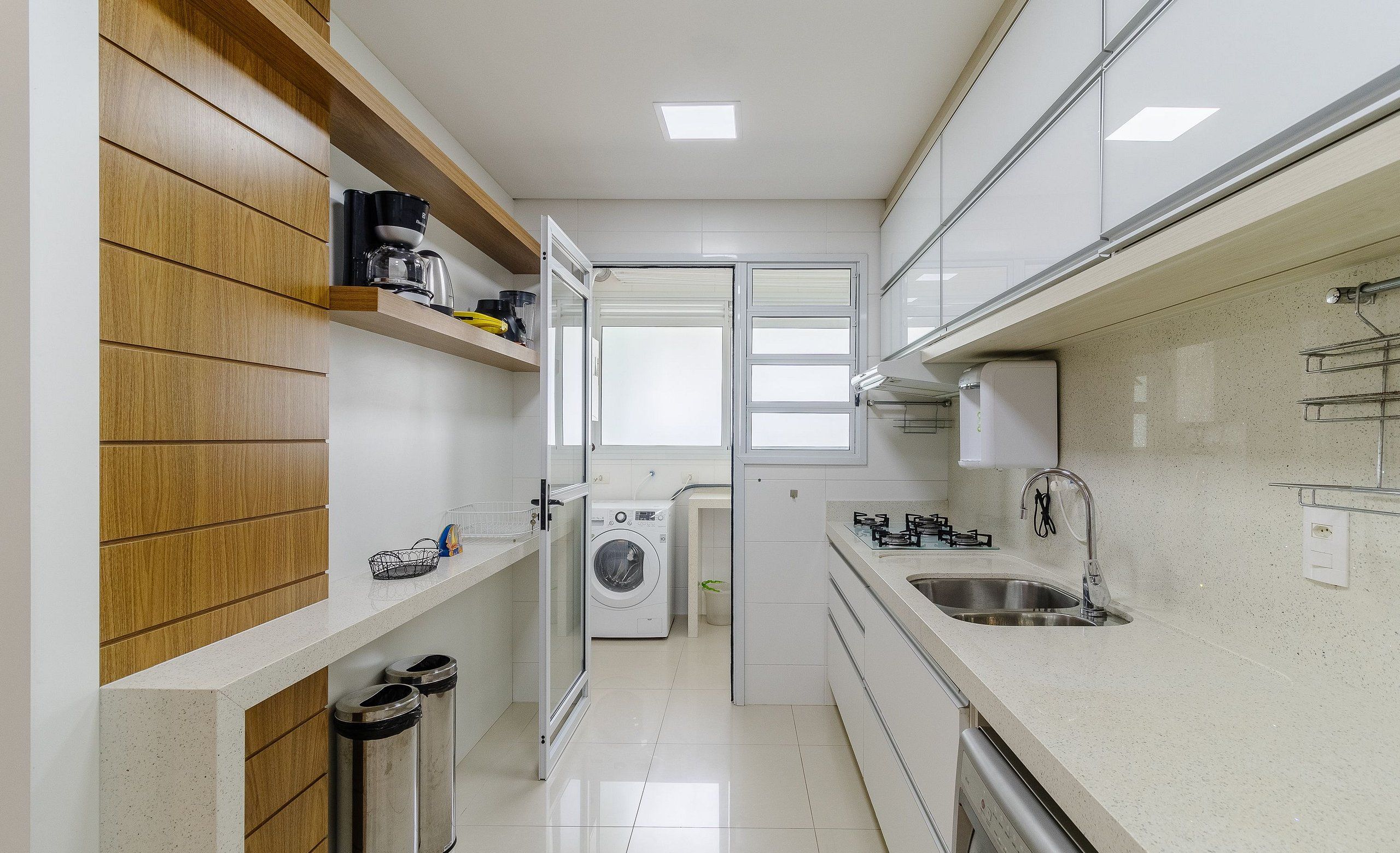 A modern kitchen with white cabinetry, a stainless steel sink, and a built-in washing machine.
