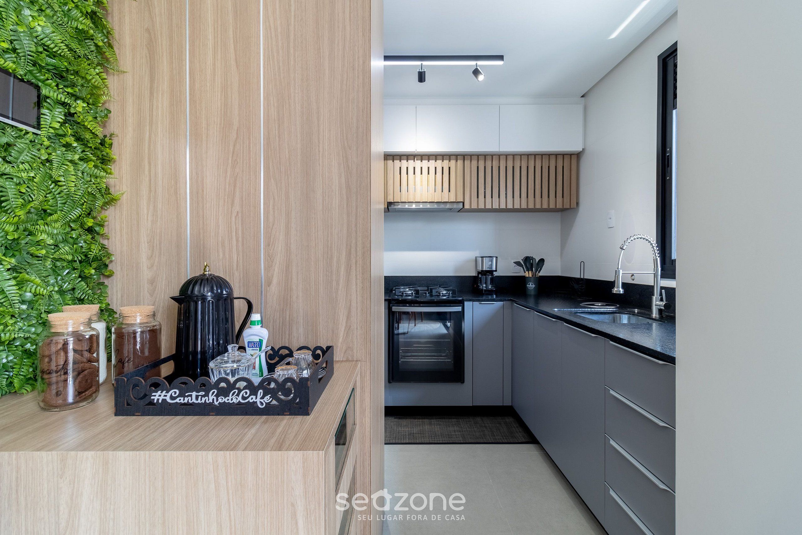 A modern kitchen with a wooden wall, a black countertop, and stainless steel appliances.