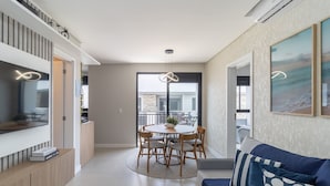 A modern living room with a round dining table, a sofa, and a view of the balcony. - Modern Apartment Near the Beach! - Atc0301 (Florianópolis)