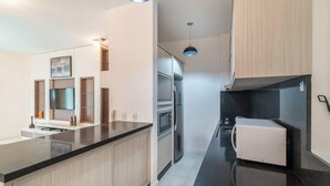 Une cuisine moderne avec un plan de travail noir, des appareils en acier inoxydable et des armoires en bois.