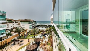 A modern hotel with a view of the ocean, outdoor seating, and a glass facade. - Beachfront Apartment w/ View Beach Santinho Asr204 (Florianópolis)