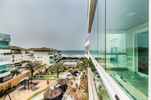 Ein modernes Hotel mit Blick auf den Ozean, Sitzgelegenheiten im Freien und einer Glasfassade.