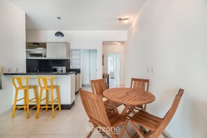 Una cocina compacta con electrodomésticos modernos, un comedor con sillas de madera y una pequeña isla con taburetes de bar.