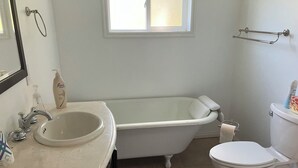 Une salle de bain avec une baignoire, des toilettes, un lavabo et une fenêtre.