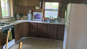Une cuisine avec des meubles de rangement en bois, une cuisinière à gaz, un évier et un réfrigérateur.
