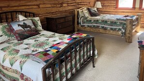 Une chambre à coucher avec deux lits en bois, une table de chevet, une commode et une fenêtre donnant sur un beau paysage.