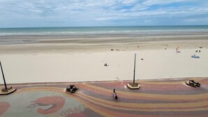 A beach with a clear sky, a sandy shore, and a few people and vehicles. - Le Mezmarine - Front de Mer (Bray-Dunes)