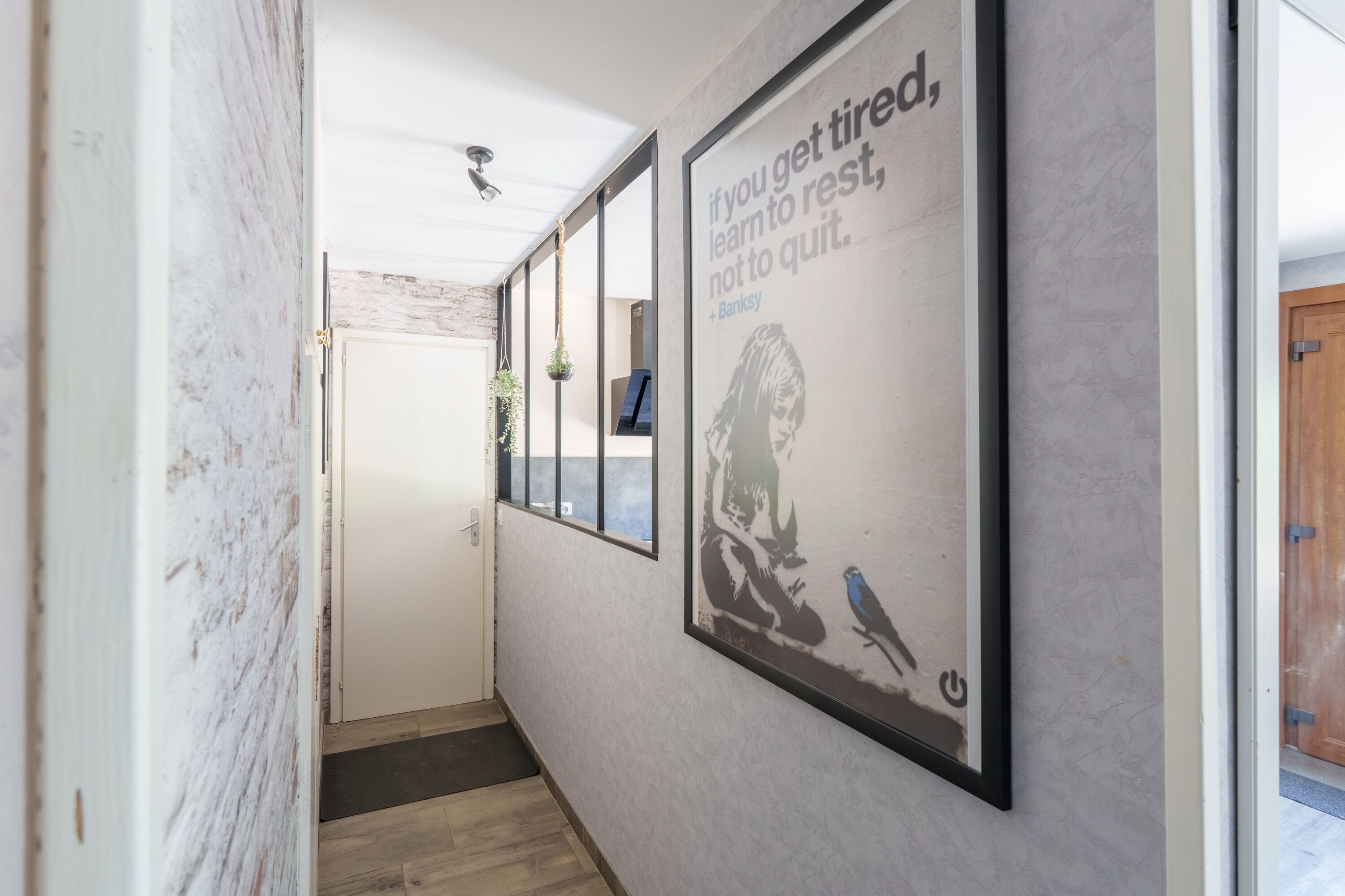 A hallway with a motivational poster, a wooden floor, and a door at the end.