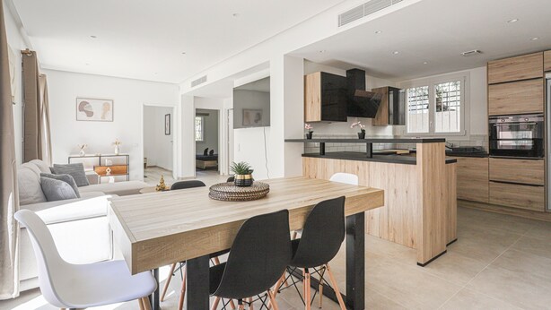 Une cuisine moderne dotée d’un îlot central, de meubles en bois et d’appareils électroménagers en acier inoxydable.