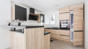 Une cuisine moderne avec des meubles en bois, un plan de travail noir et un four encastré.
