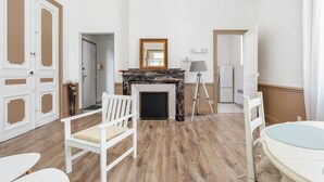 A room with a fireplace, white furniture, and wooden flooring. - Le Parc de la Révolution - Proche Gare (Narbonne)