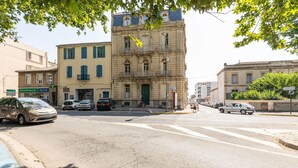 A street view with a prominent building featuring a balcony and a pharmacy sign. - Le Parc de la Révolution - Proche Gare (Narbonne)