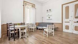 A dining area with a wooden table and chairs, a grey sofa, and a small side table. - Le Parc de la Révolution - Proche Gare (Narbonne)