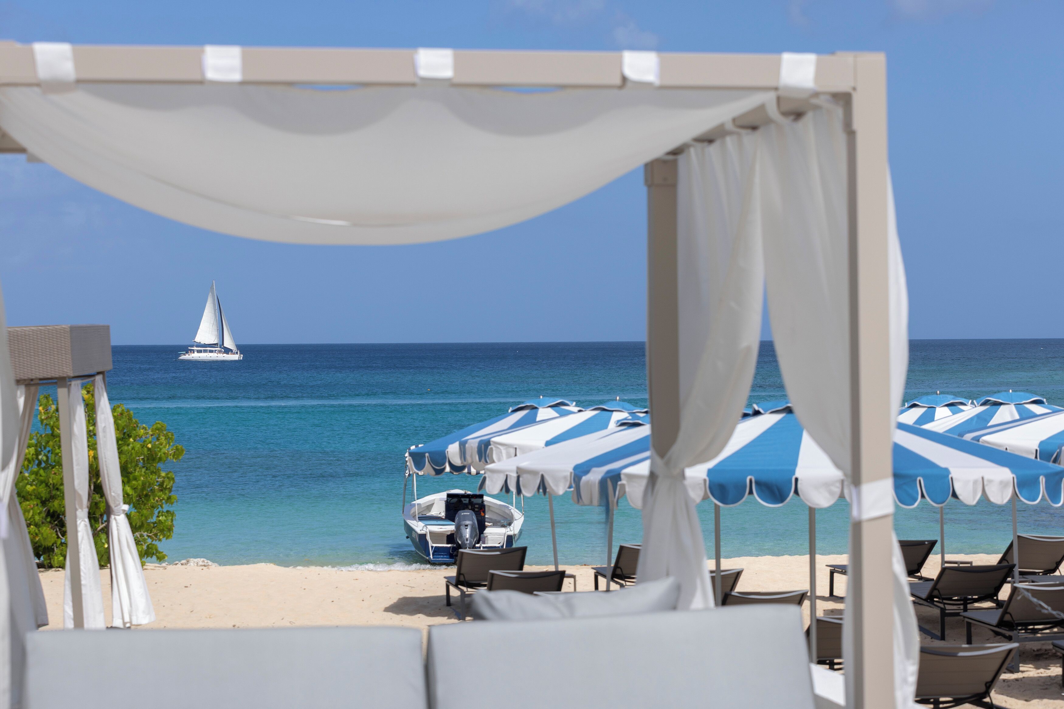 A beach with a boat, umbrellas, and lounge chairs.