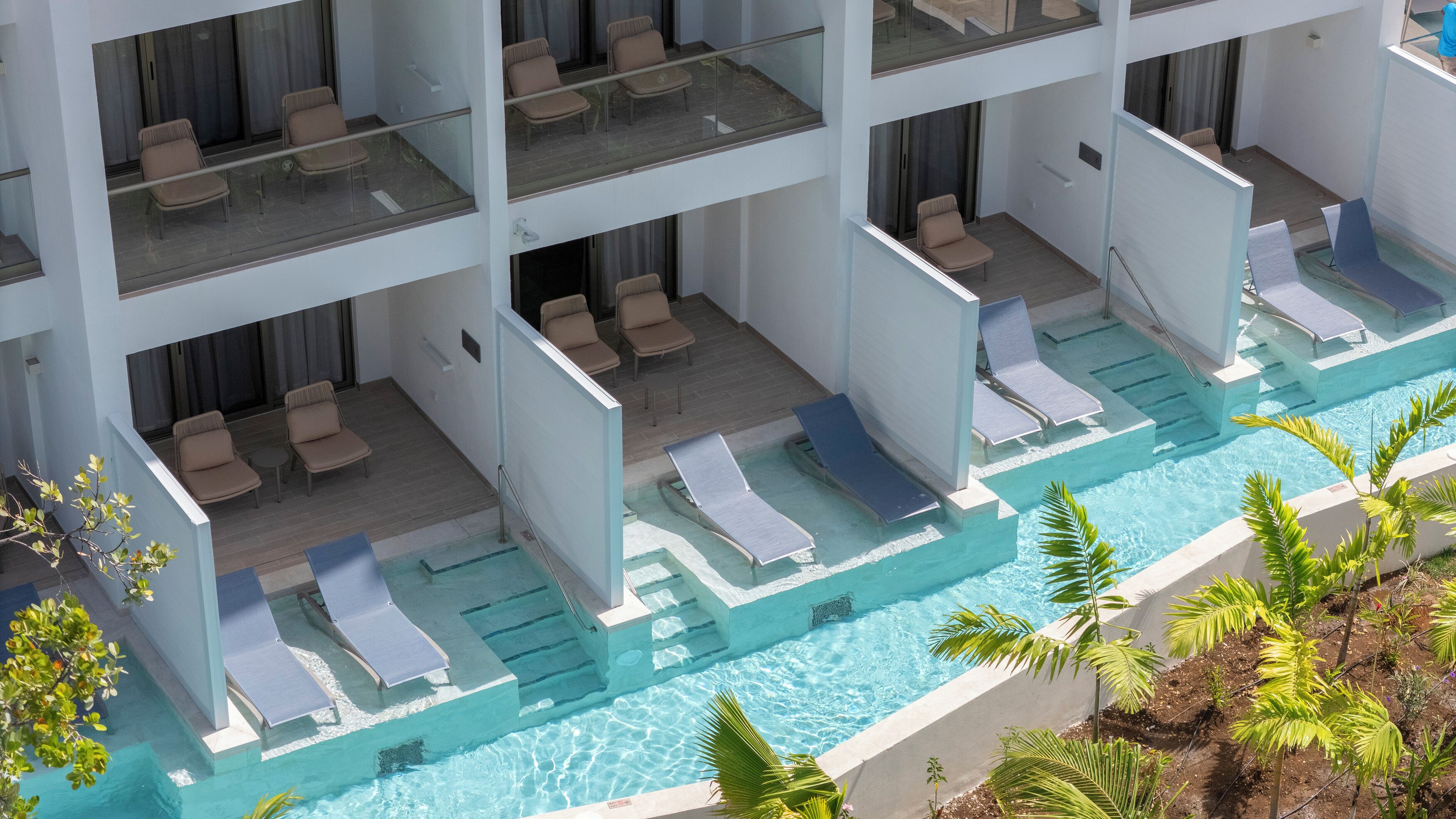 Un hotel de varios niveles con piscina, sillas de descanso y vistas a la piscina desde arriba.