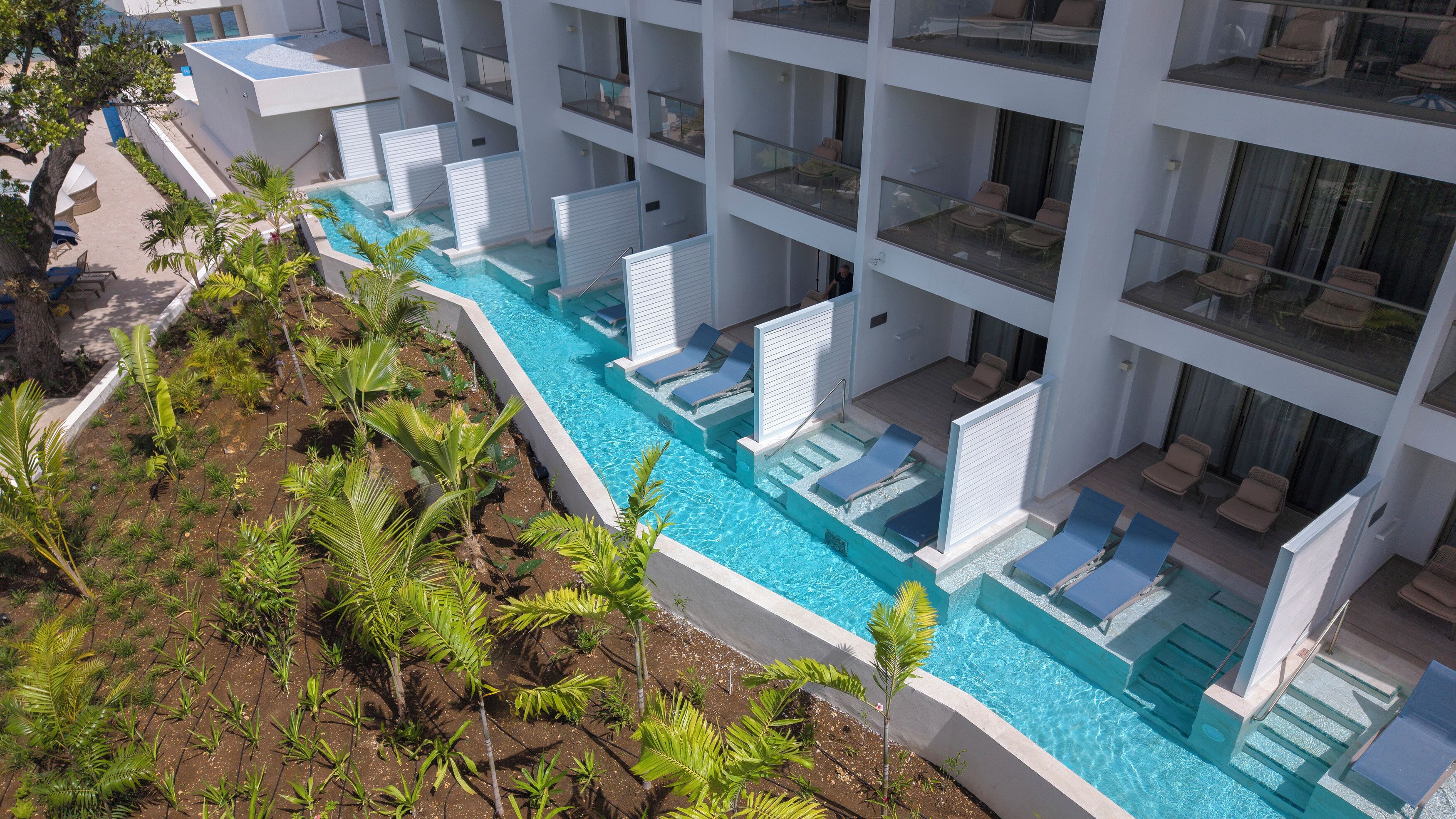 Un hôtel moderne doté d’une piscine sur le toit, de nombreux balcons et d’une végétation luxuriante.