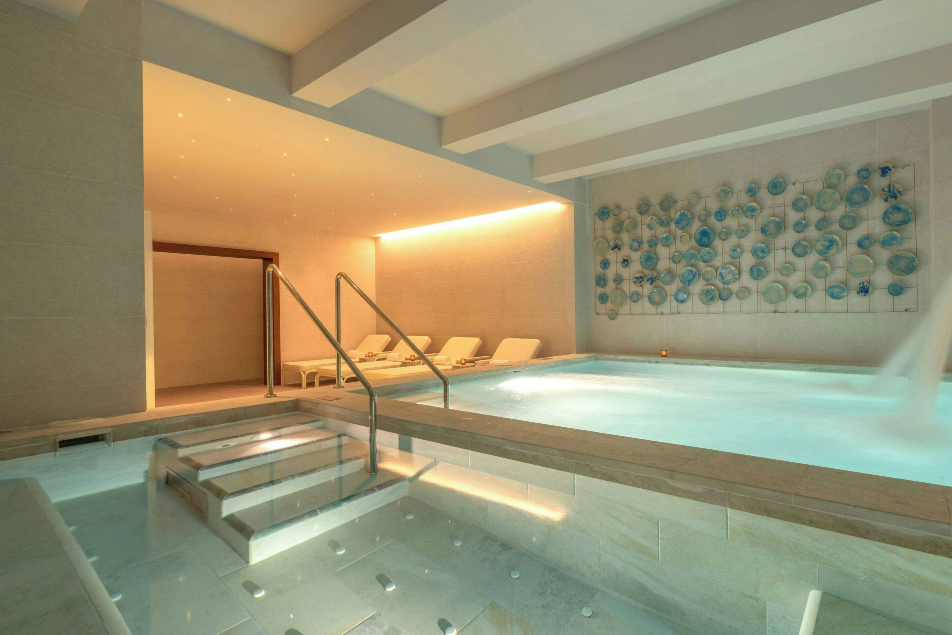 A spa area with a hot tub, a wall of decorative plates, and a staircase leading to a lounge area.