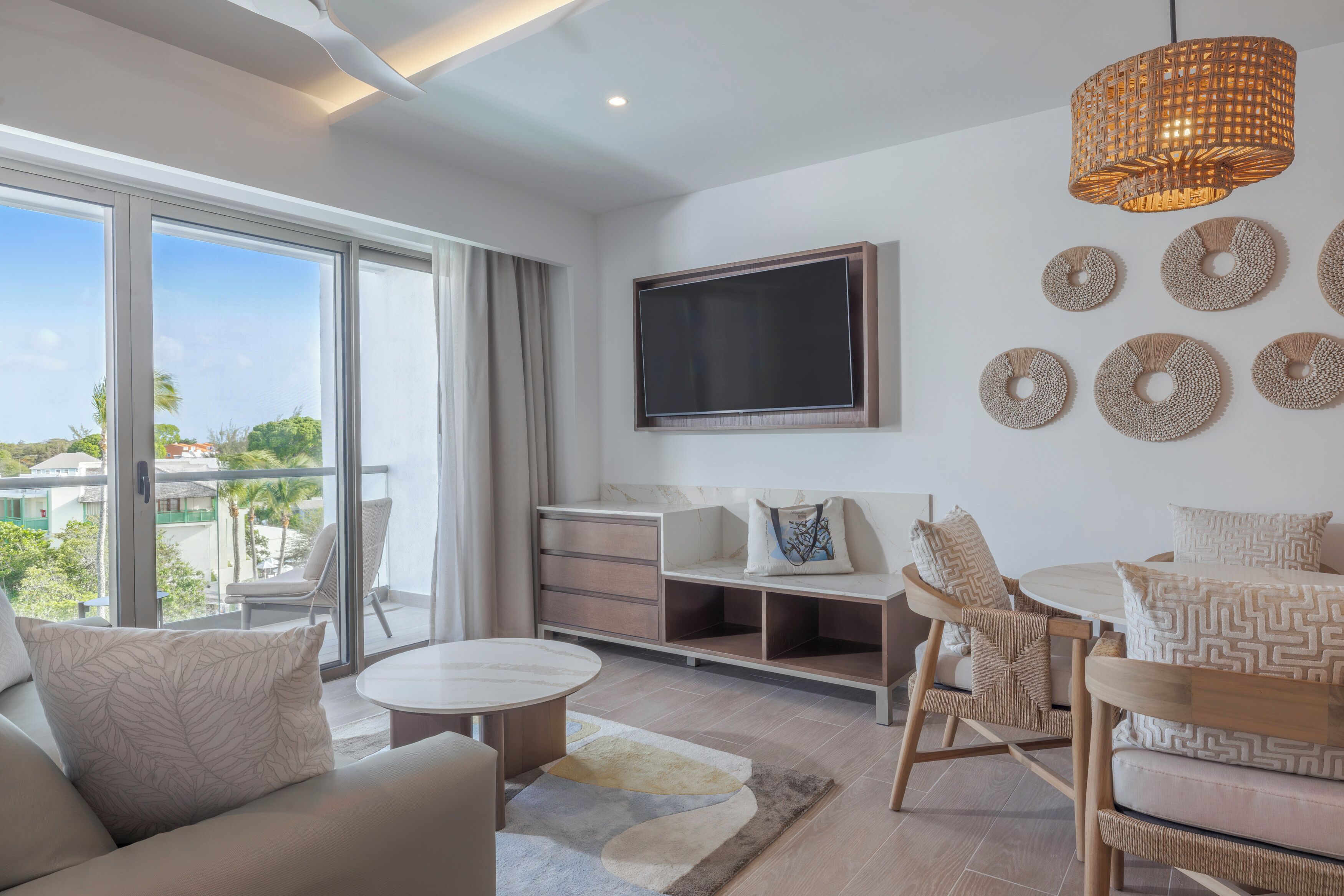 Una sala de estar moderna con un televisor grande, asientos cómodos y vistas al exterior.