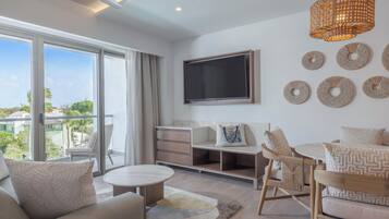 Una sala de estar moderna con un televisor grande, asientos cómodos y vistas al exterior.