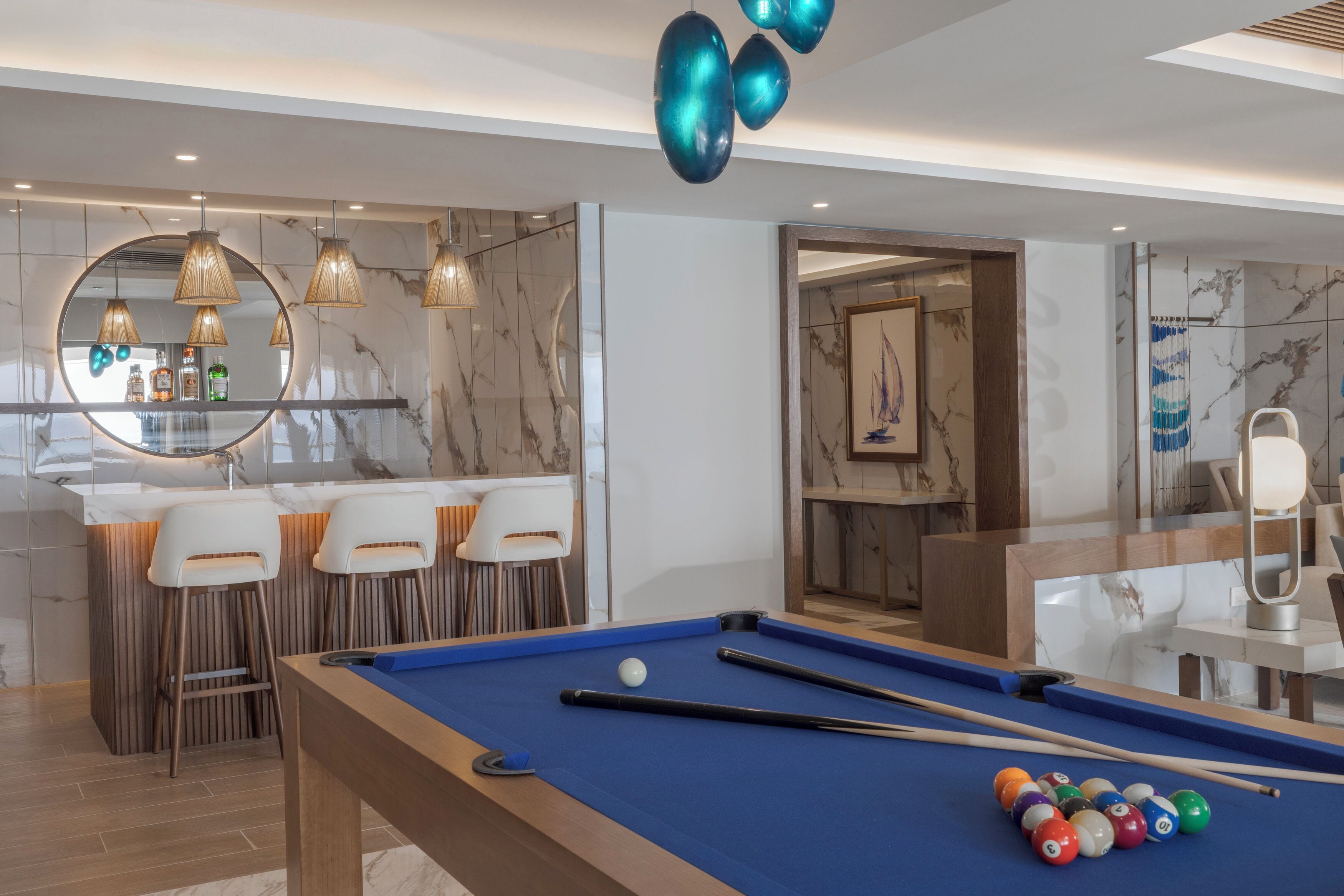 Uma mesa de bilhar com bolas, um espaço de bar com cadeiras e um espelho.