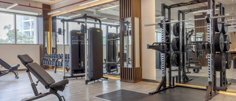 Ein Fitnessraum mit Gewichthebern, einer Bank und Kurzhanteln.