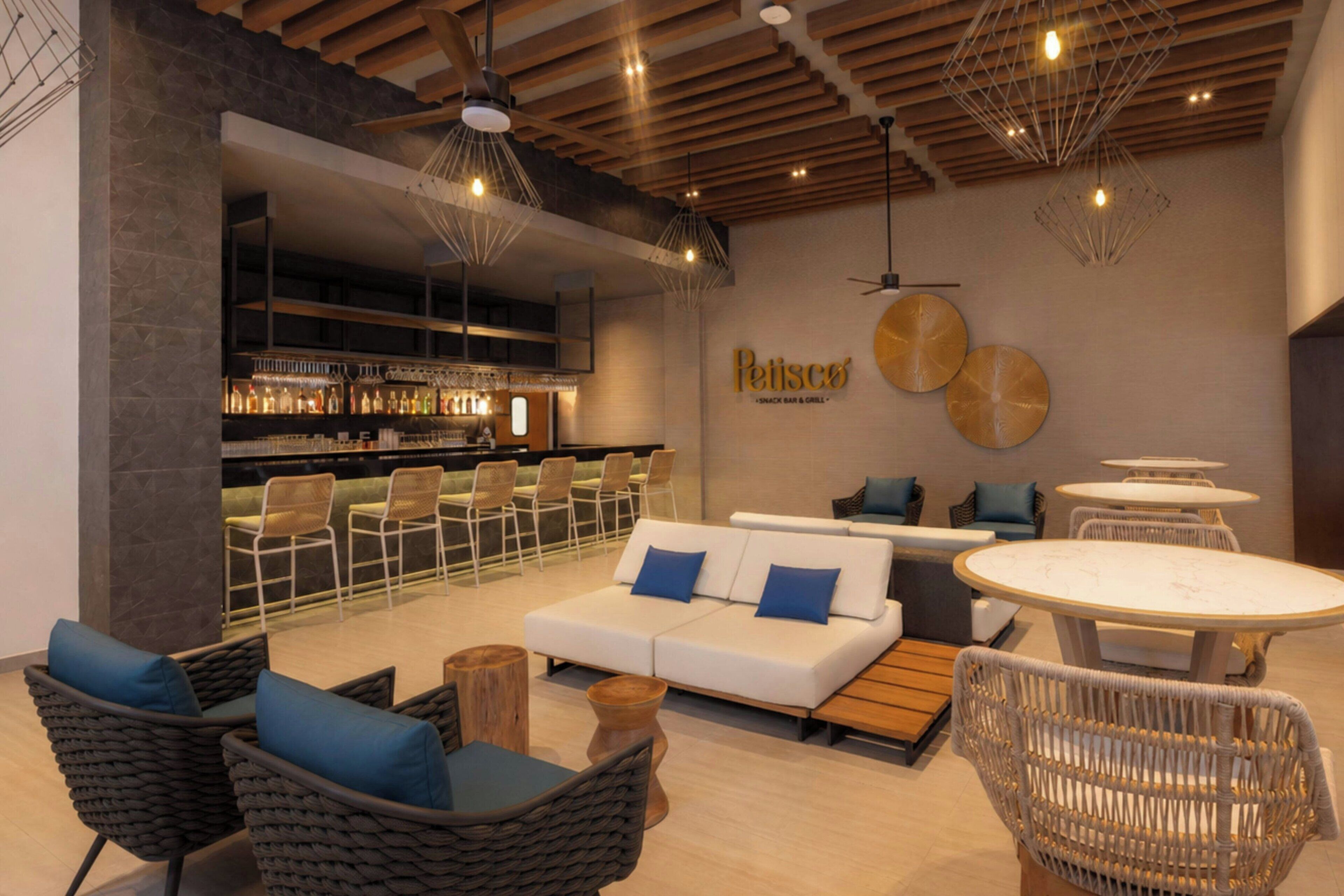 A modern lounge area with a bar, seating, and a visible restaurant sign.