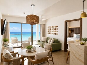 Un amplio salón con un ventanal grande con vistas al océano, un sofá verde, una mesa de comedor con sillas y una cocina con encimera de mármol.
