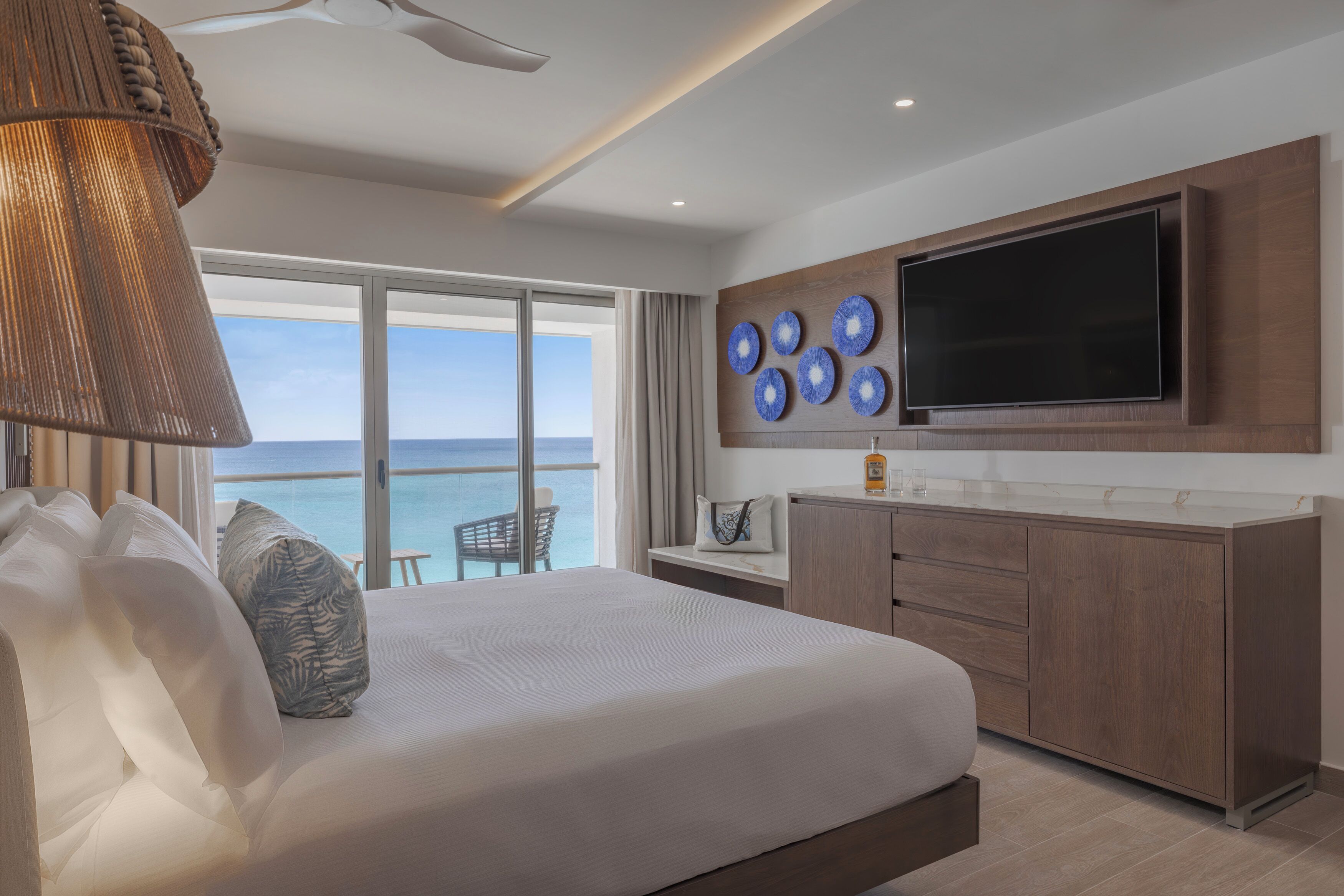 Une chambre d’hôtel avec un lit, une télévision, un minibar et une vue sur la mer.