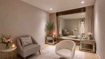 Una habitación moderna con sofá, sillón, espejo y un perchero para vestidos.
