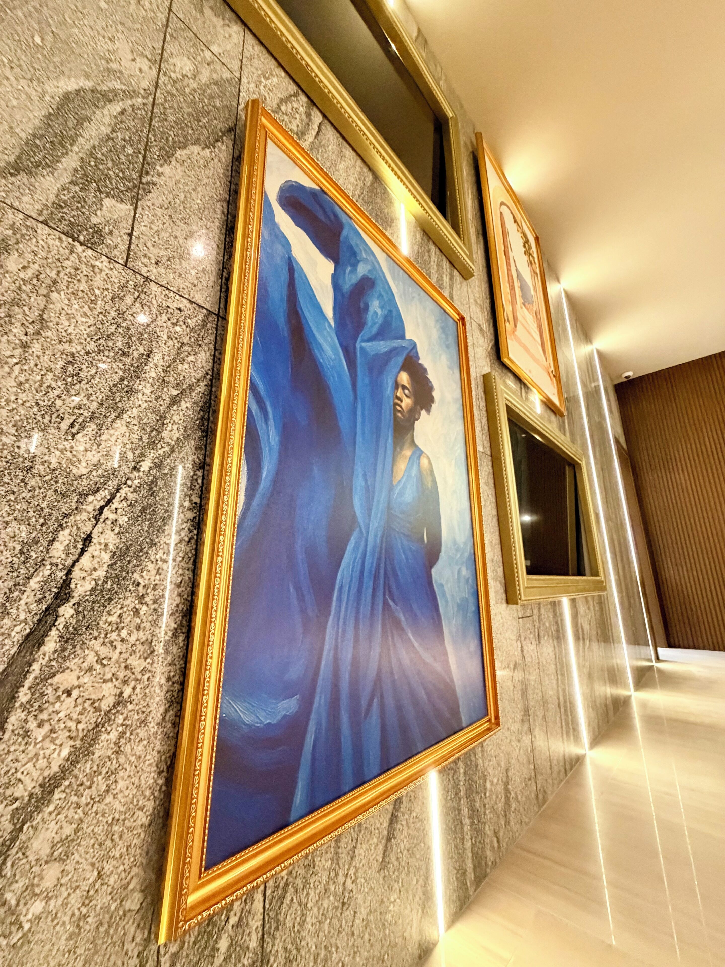 A marble wall with framed artwork and mirrors.