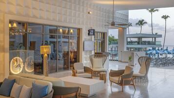 A modern lounge area with seating, a TV, and a view of the beach.