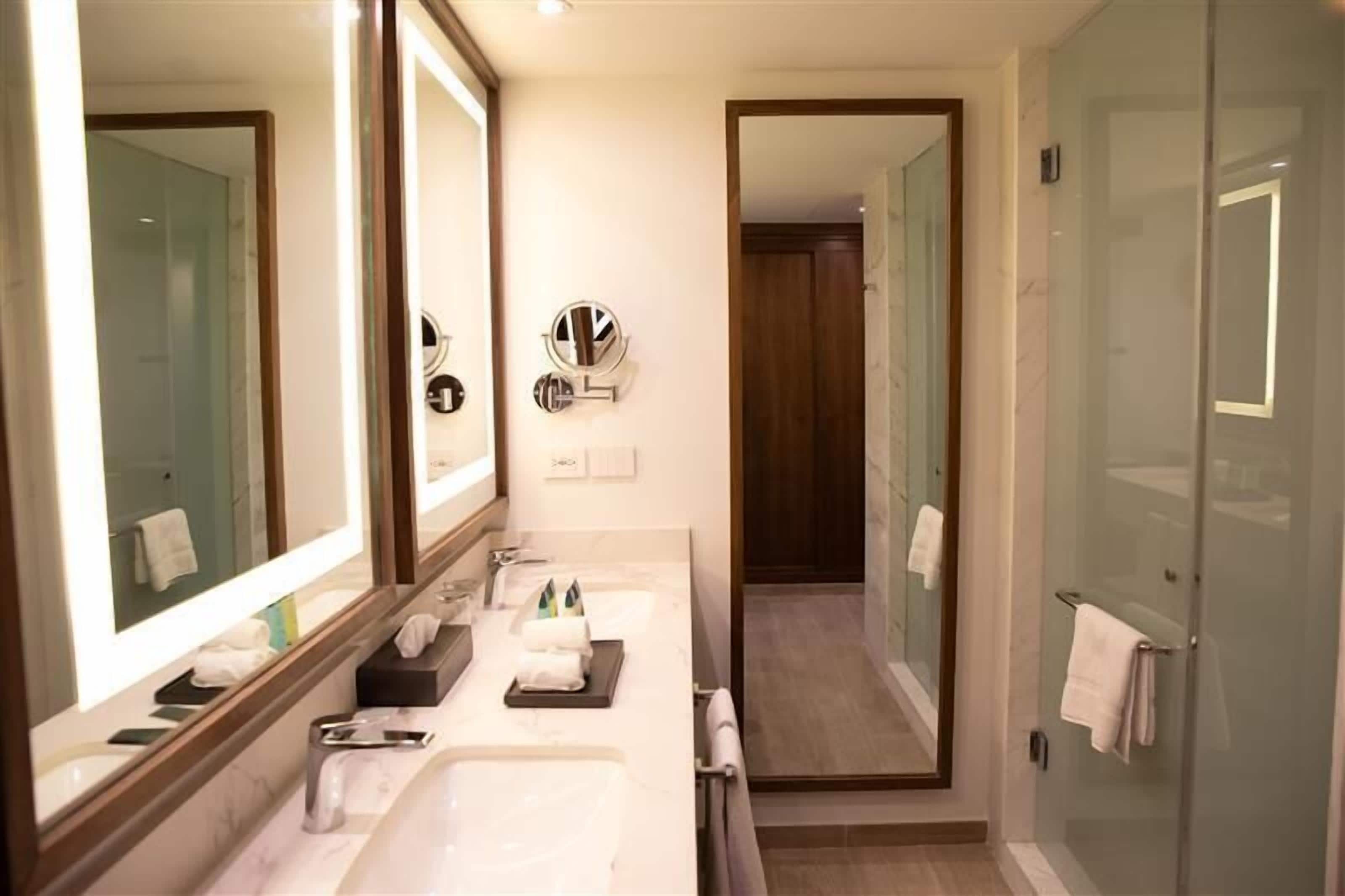 Un baño moderno con dos lavamanos, un espejo grande y una cabina de ducha de vidrio.