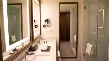 A modern bathroom with two sinks, a large mirror, and a glass shower enclosure.