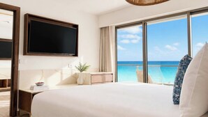 Habitación de hotel con una cama grande, televisión de pantalla plana, vista al océano y un balcón con barandilla.