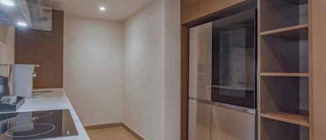 A modern kitchen with a built-in stove, a glass-fronted refrigerator, and wooden cabinetry.