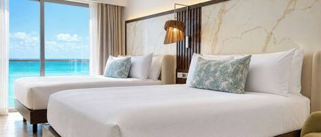 A hotel room with two beds, a large window with a view of the ocean, a marble wall, and a modern lamp.