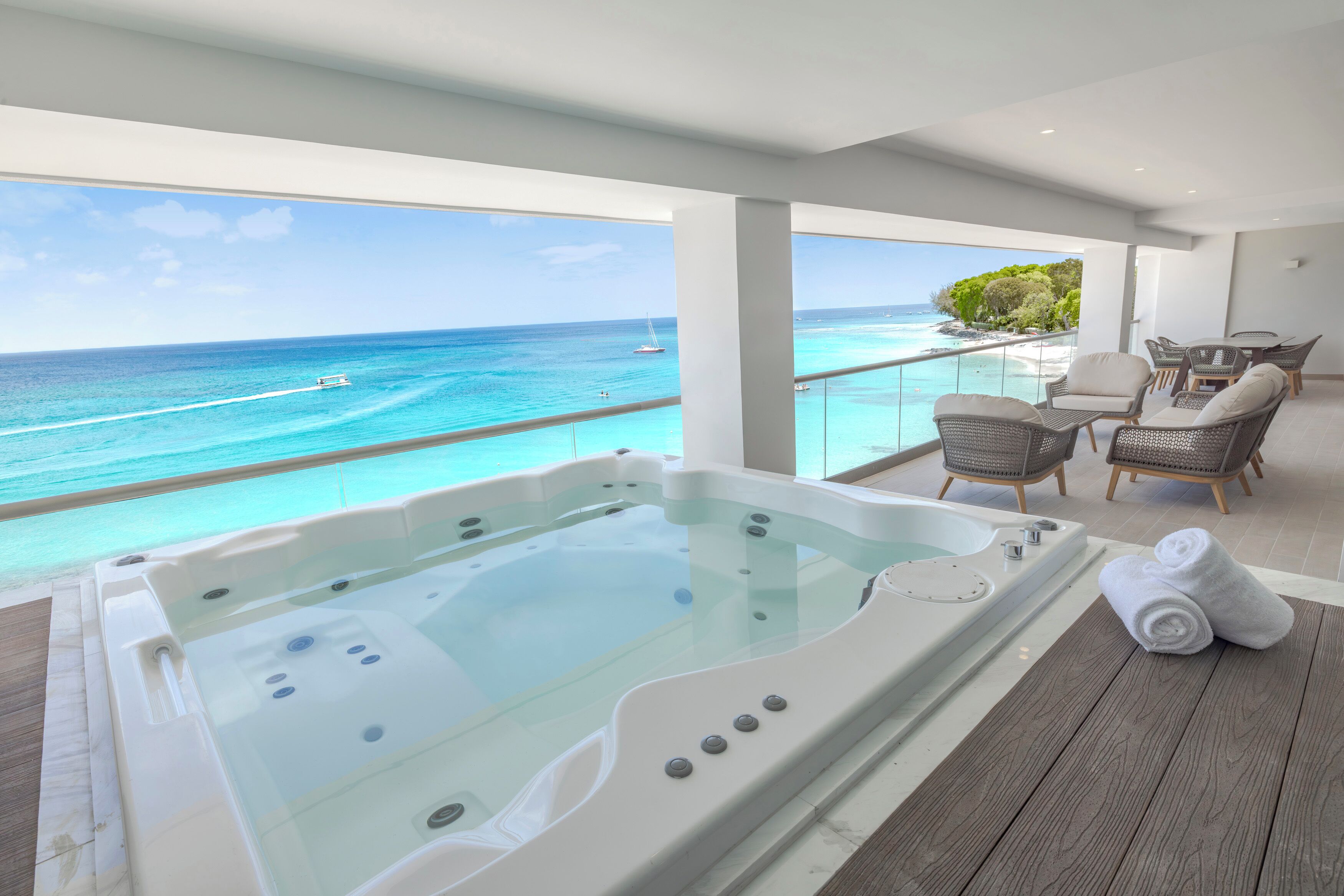 A balcony with a hot tub, outdoor seating, and a view of the ocean.