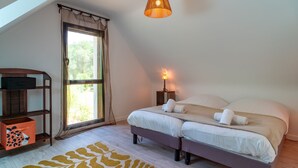 A bedroom with a bed, bedside table, lamp, and a window with curtains. - Maison Kerzuc - Entre mer et forêt (Crac'h)