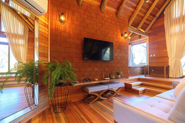 Un salon chaleureux avec un mur en briques, un plancher en bois, un téléviseur à écran plat et un coin salon confortable.